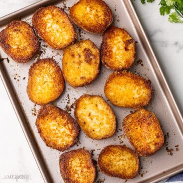 large pan of roasted potatoes with parsley beside it.
